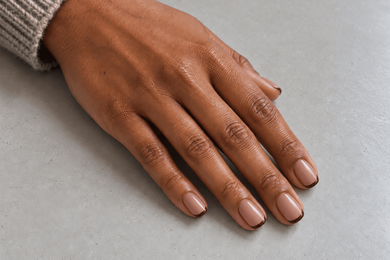 Short pink-beige nails outlined with narrow espresso-brown French tips.