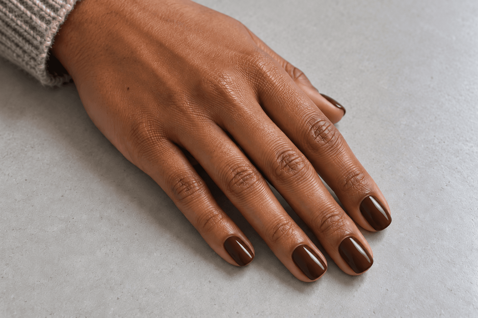 Short squoval nails in a rich medium-deep chocolate brown, shown against neutral gray.