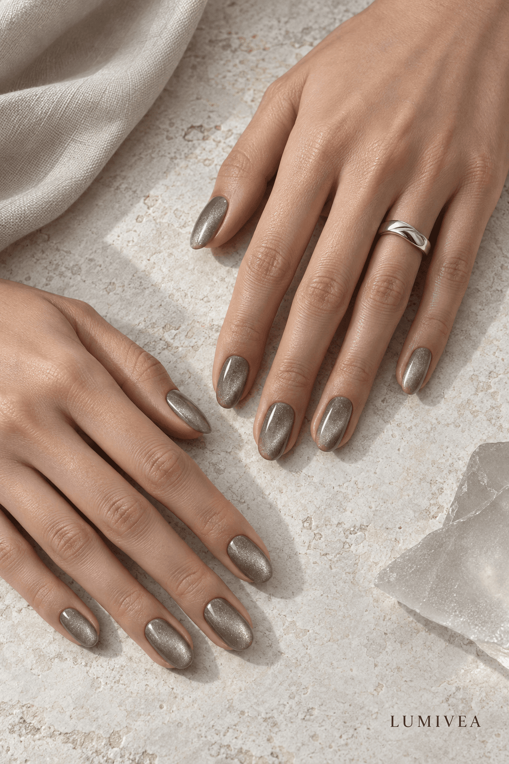 Taupe magnetic velvet oval nails photographed on pale limestone with a small Lumivea logo