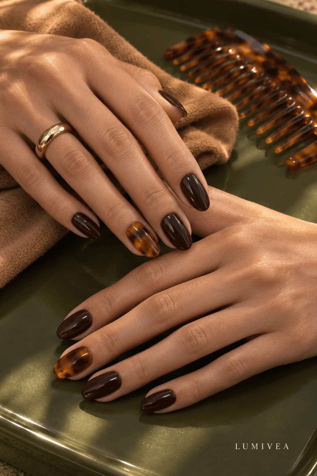 Tortoise-shell and glossy espresso oval nails on a dark-olive surface with a small Lumivea logo
