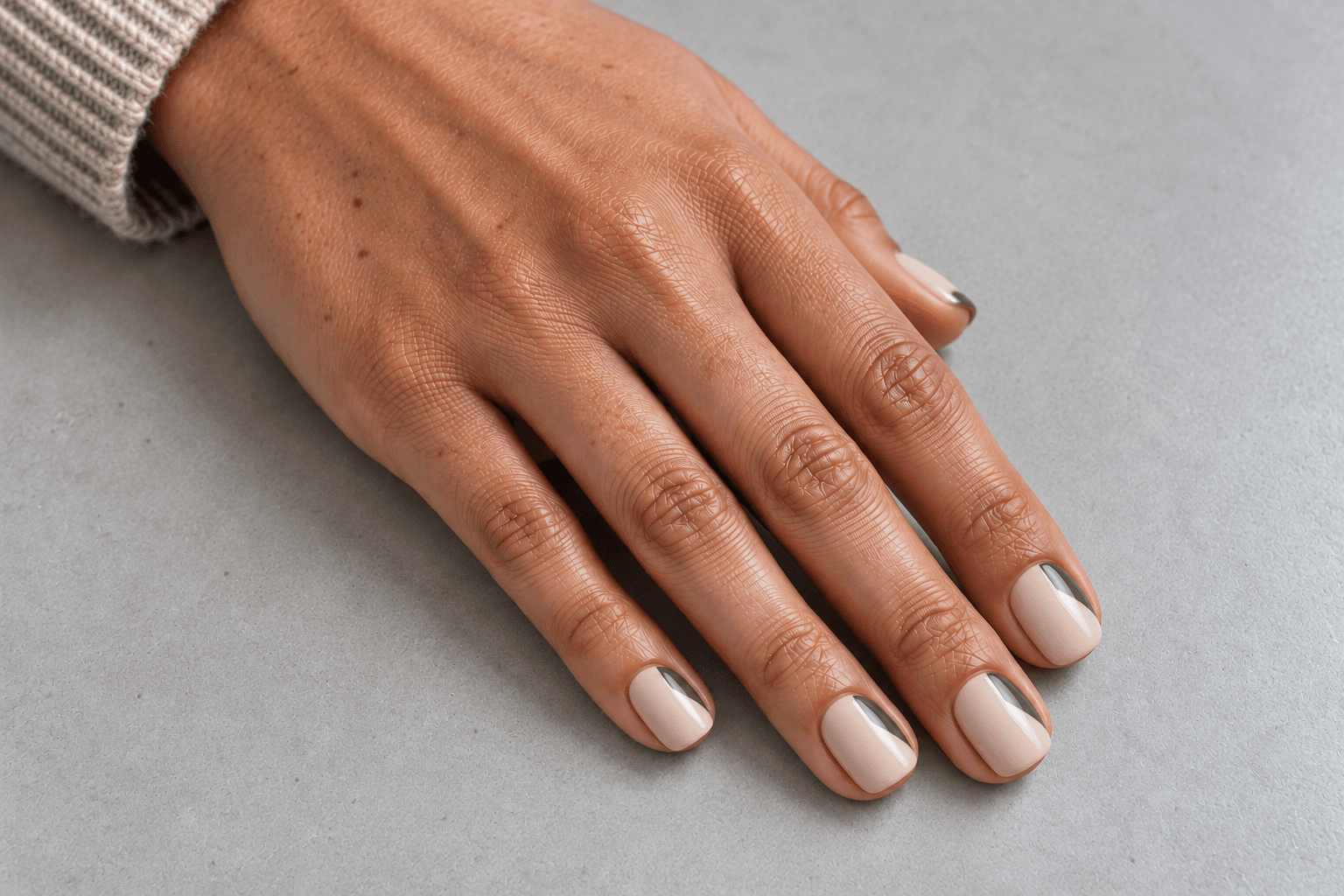 Short pale beige nails with small diagonal olive-green blocks at the tip corners.