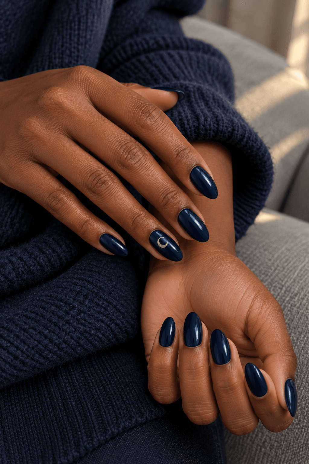 Midnight-blue almond nails with a small silver crescent on one ring nail.