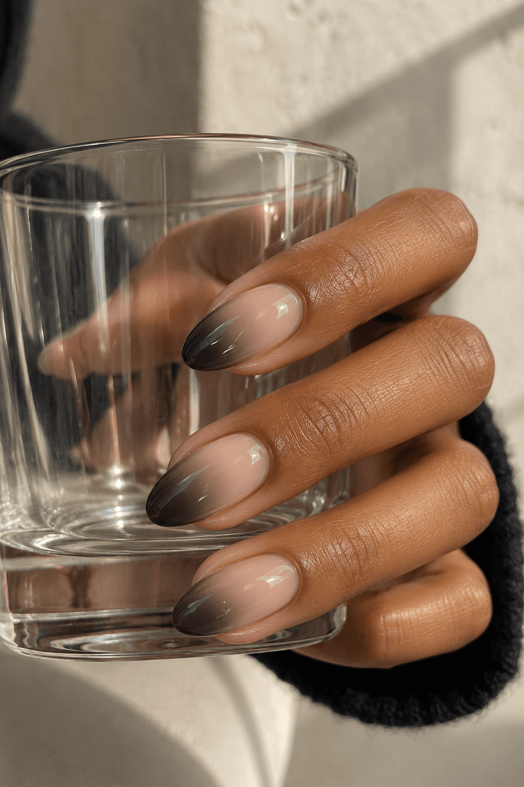 Pink-beige almond nails fading into smoky charcoal at the tips.